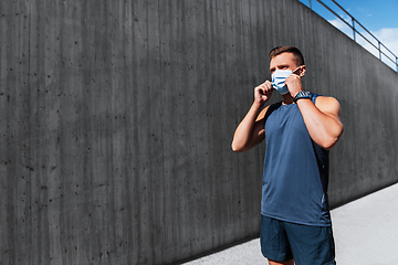 Image showing young man in medical mask doing sports outdoors