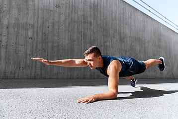 Image showing young man doing plank on city street