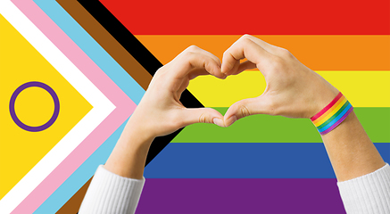 Image showing couple showing hand heart over progress pride flag