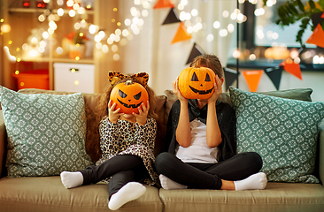 Image showing girls in halloween costumes with pumpkins at home