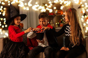 Image showing kids in halloween costumes sharing candies at home