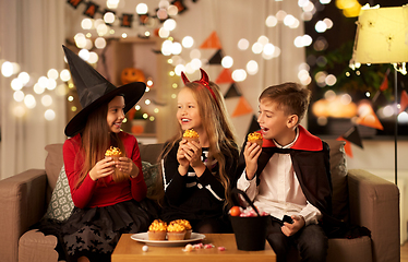 Image showing kids in halloween costumes eating cupcakes at home