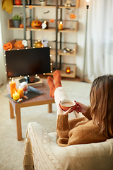 Image showing woman watches tv and drinks cocoa on halloween