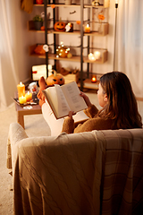 Image showing young woman reading book at home on halloween