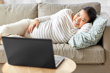 Image showing happy pregnant asian woman with laptop at home