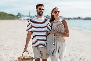 Image showing happy couple with picnic basket walking on beach