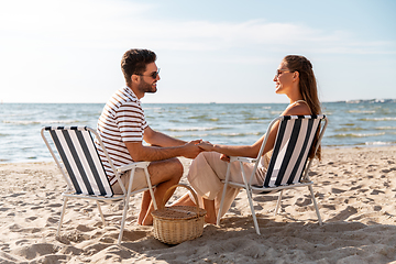 Image showing happy couple sitting in folding chairs on beach