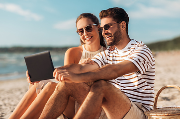 Image showing happy couple with tablet pc at picnic on beach