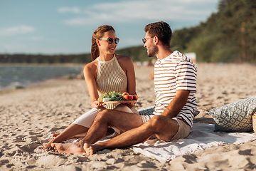 Image showing happy couple with food having picnic on beach