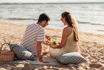 Image showing happy couple with food having picnic on beach