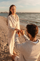 Image showing man with ring making proposal to woman on beach