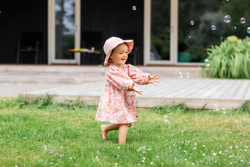 Image showing happy baby girl playing with soap bubbles outdoors