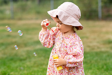 Image showing happy baby girl blowing soap bubbles in summer