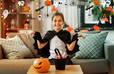 Image showing girl in halloween costume with bat cape at home