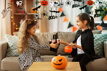 Image showing girls in halloween costumes with candies at home