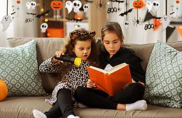 Image showing girls in halloween costumes reading book at home