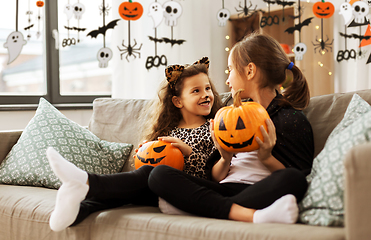 Image showing girls in halloween costumes with pumpkins at home