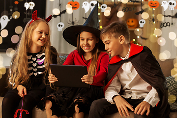 Image showing kids in halloween costumes with tablet pc at home