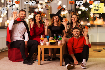 Image showing happy friends in halloween costumes at home party