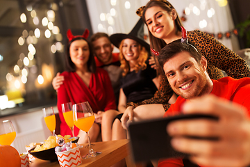 Image showing happy friends in halloween costumes taking selfie