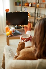 Image showing woman watches tv and drinks cocoa on halloween