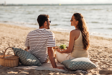 Image showing happy couple with food having picnic on beach