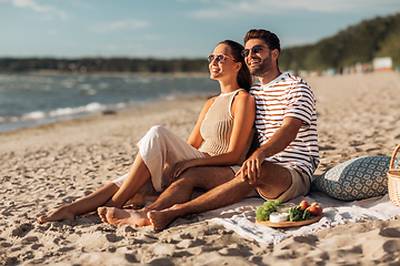 Image showing happy couple with food having picnic on beach