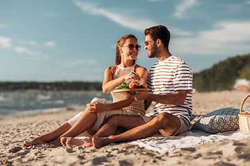 Image showing happy couple with food having picnic on beach