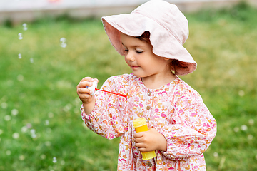 Image showing happy baby girl blowing soap bubbles in summer