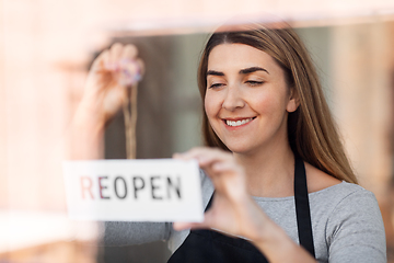 Image showing happy woman hanging reopen banner to door glass