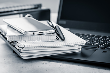 Image showing Office table - stack of notebooks, cellphone with laptop