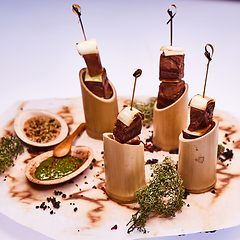 Image showing Grilled pork meat with sauce inserted with bamboo sticks. Shallow dof