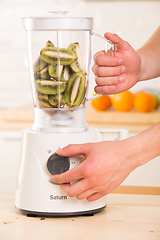 Image showing Young man cooking kiwi smoothie in blender