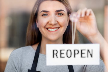 Image showing happy woman hanging reopen banner to door glass