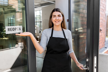 Image showing happy woman showing reopen banner on door glass