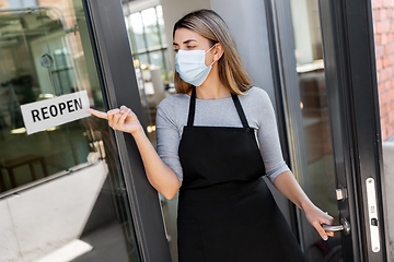 Image showing woman in mask showing reopen banner on door glass