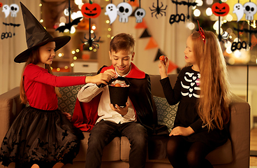 Image showing kids in halloween costumes share candies at home