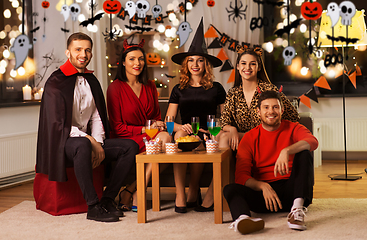 Image showing happy friends in halloween costumes at home party