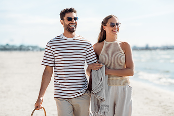 Image showing happy couple with blanket walking along beach