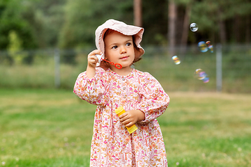 Image showing happy baby girl blowing soap bubbles in summer