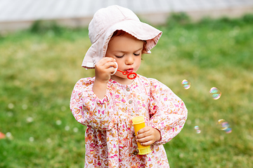 Image showing happy baby girl blowing soap bubbles in summer