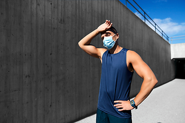 Image showing tired man in medical mask doing sports outdoors