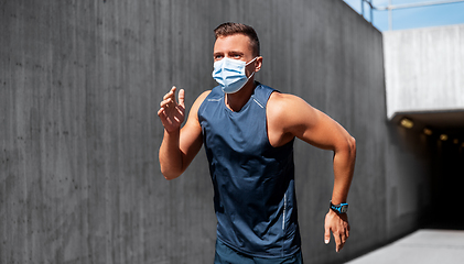 Image showing young man in medical mask running outdoors