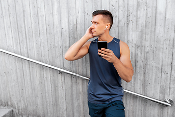 Image showing young athlete man with earphones and smartphone