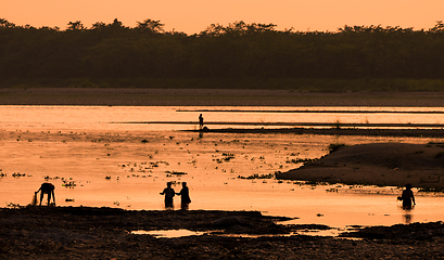 Image showing Asian women fishing in the river, silhouette at sunset