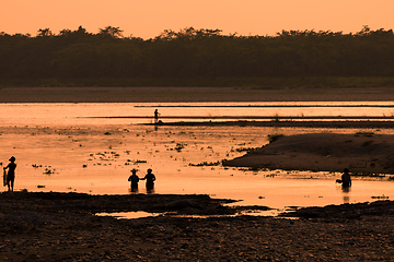 Image showing Asian women fishing in the river, silhouette at sunset