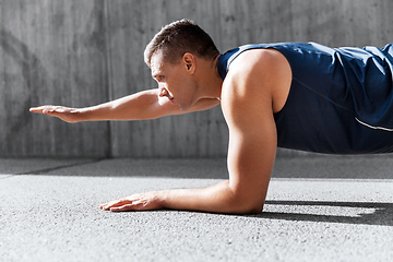 Image showing young man doing plank on city street