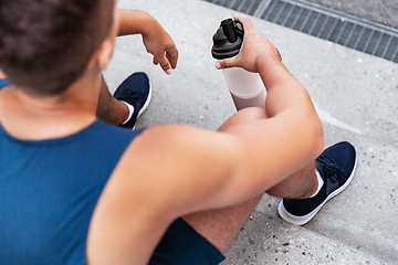 Image showing sportsman with shake in bottle sitting on stairs