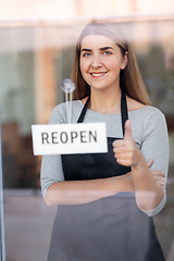 Image showing happy woman hanging reopen banner to door glass