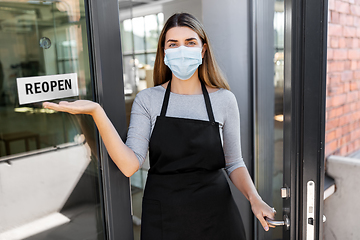 Image showing woman in mask showing reopen banner on door glass